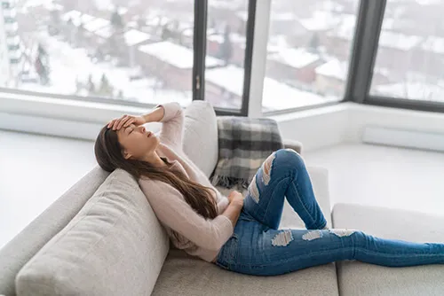 Woman resting on a couch with chronic pain