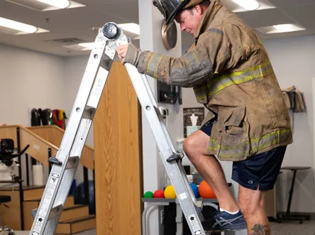 Firefighter climbing a ladder during a functional capacity evaluation