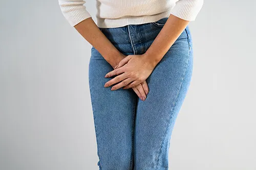 Woman holding her pelvis, representing pelvic floor and bladder concerns