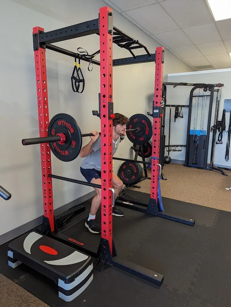 Patient performing a barbell squat in the strength training rack