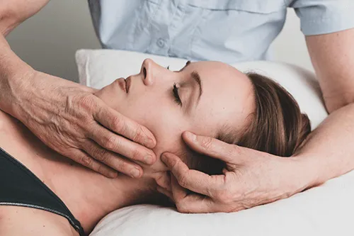 Therapist providing hands-on TMJ treatment along a patient’s jaw