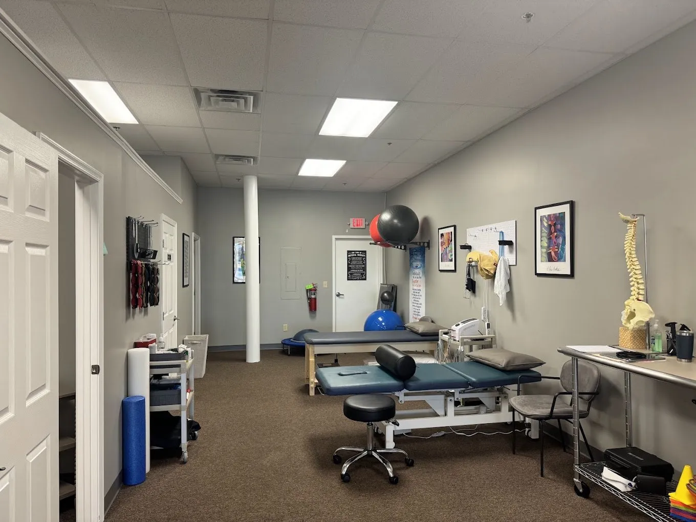 Treatment room with tables, therapy balls, and a spine model